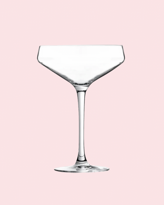 Clear wine glass on a pink background