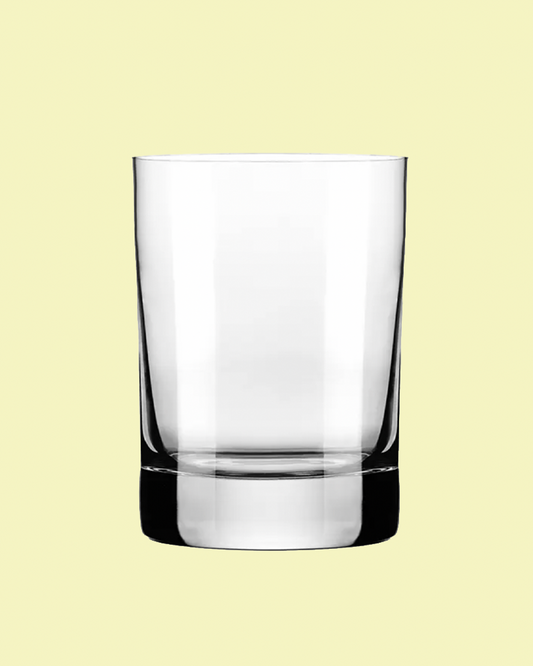 Clear glass tumbler on a light yellow background