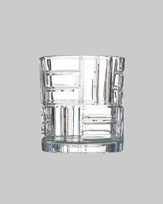Clear glass tumbler with textured design on a gray background