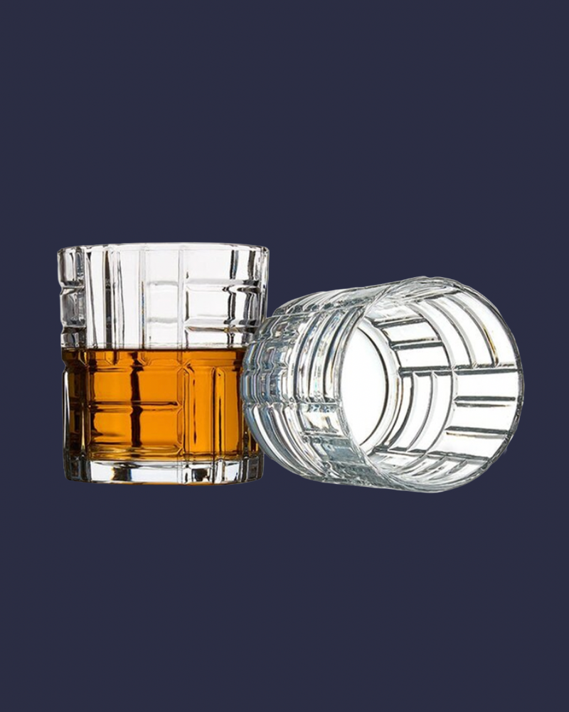 Clear glass with whiskey and another clear glass on a dark blue background