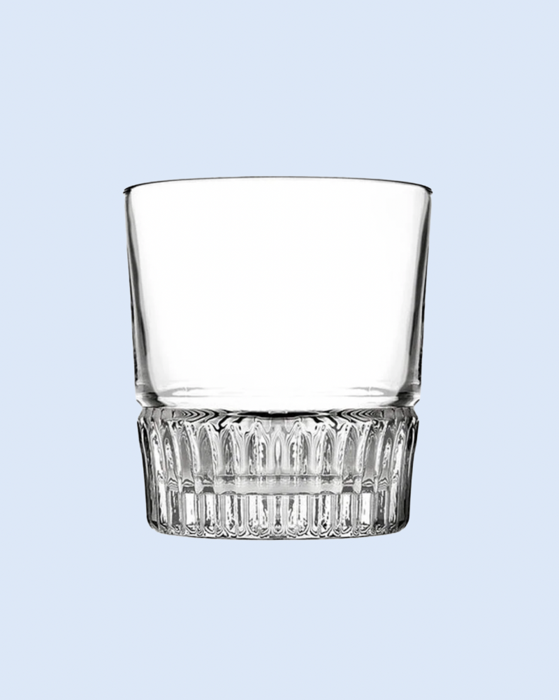 Clear glass tumbler with decorative base on a light blue background