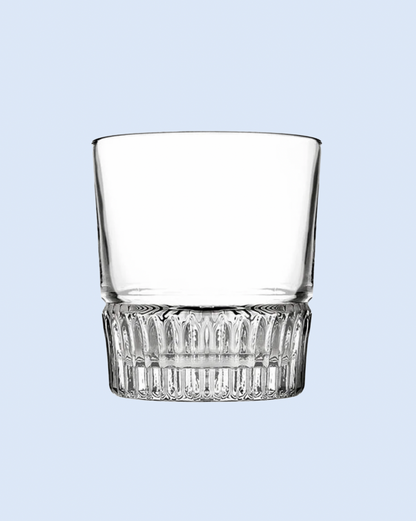 Clear glass tumbler with decorative base on a light blue background