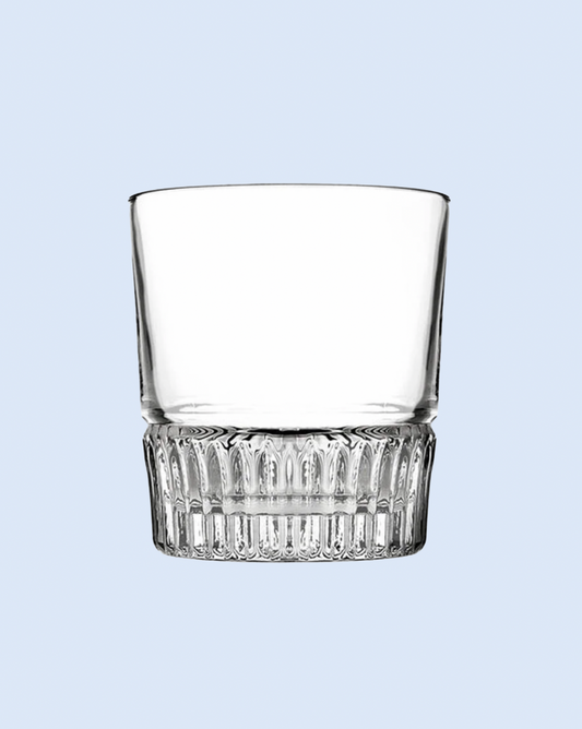 Clear glass tumbler with decorative base on a light blue background