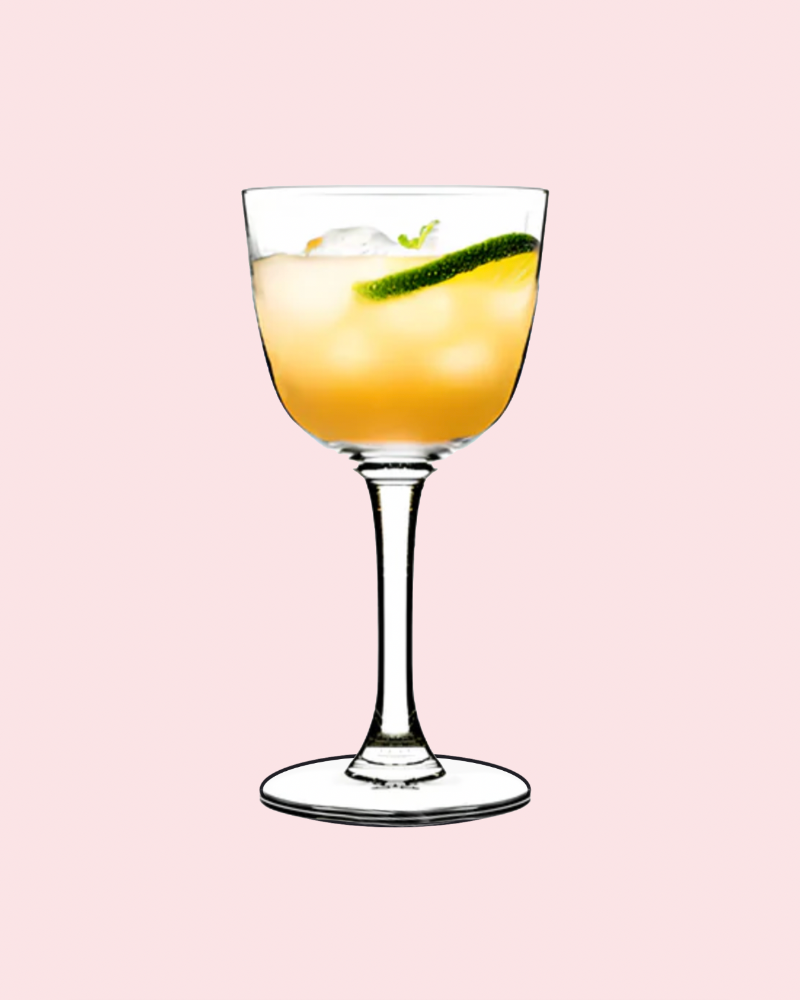 Cocktail in a glass with a lime wedge on a pink background