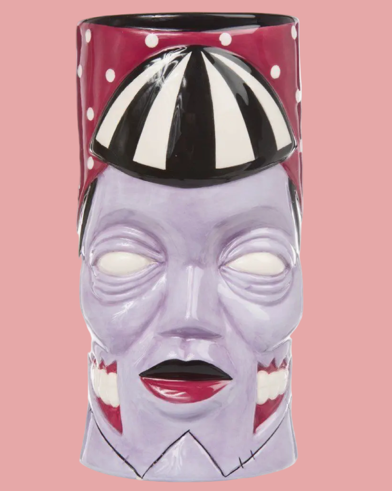 Vase with a face design and black and white striped hat on a pink background