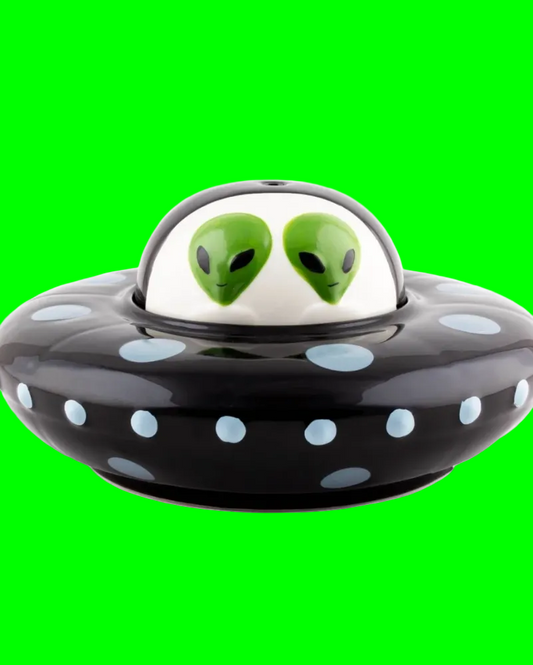 A ceramic UFO-shaped container or dish with a glossy black body, light blue polka dots, and a white dome top featuring two green alien faces. The product is shown on a plain white background with a 'Click to expand' overlay in the bottom right corner.