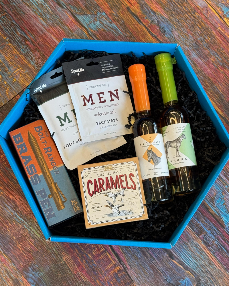 Gift set with men's grooming products and snacks in a blue box on a wooden surface